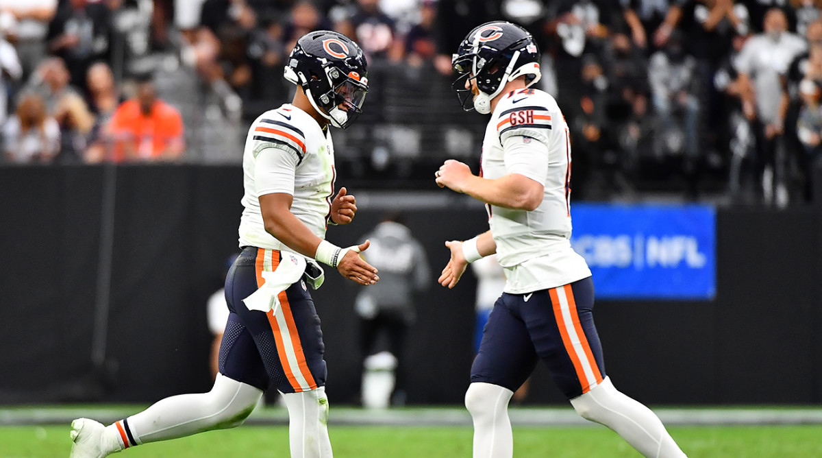 Bears quarterback Justin Fields (1) greets Bears quarterback Andy Dalton (14) as he returns to the field.